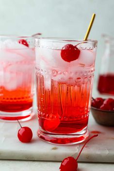 two glasses filled with red liquid and cherries