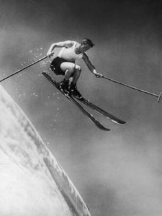 a man riding skis down the side of a snow covered slope in mid air