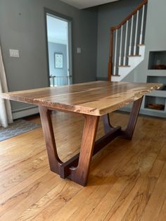 a wooden table sitting on top of a hard wood floor next to a stair case