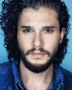 a man with curly hair and beard wearing a blue shirt