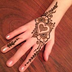 a woman's hand with henna tattoos on it and a heart in the middle