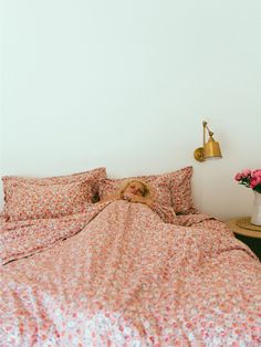 a woman laying in bed with her head on the pillow next to an alarm clock