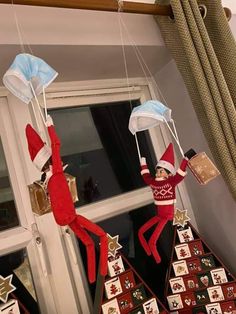 two elfs hanging from the ceiling in front of a window