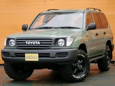 a green toyota suv parked in front of a yellow building with the word toyota written on it