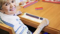 an older woman sitting at a table with pencils