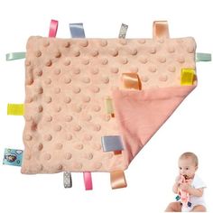 a pink blanket with various colored clips on it and a baby's face next to it