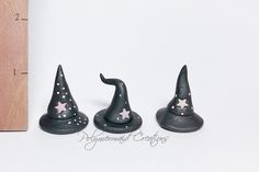 three small black witches hats sitting on top of a white table next to a ruler