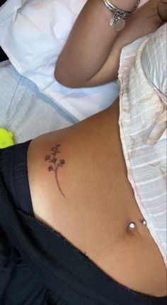 a woman's stomach with a small flower tattoo on her lower back and side