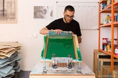 a man working on a machine in a room full of stacks of books and papers