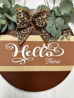 a door hanger that says hello there with a leopard print bow on the front