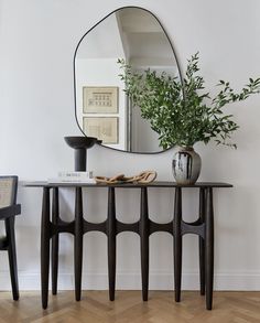 a table with a mirror and vase on it