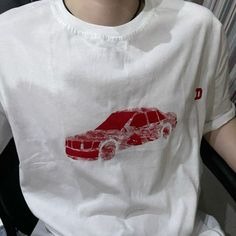 a person wearing a white shirt with a red car on it