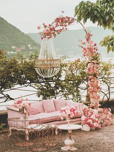 an outdoor seating area with pink flowers and chandelier