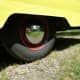 the rear end of a yellow car with its reflection in it