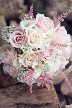 a bridal bouquet with pink roses and baby's breath in the center is sitting on wood