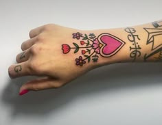 a woman's arm with tattoos on it and flowers around the wrist, which is decorated with hearts