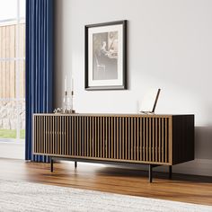 a wooden sideboard sitting on top of a hard wood floor next to a window