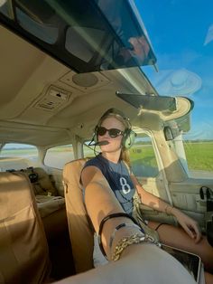 a woman sitting in the back seat of a car with headphones on and looking at the camera