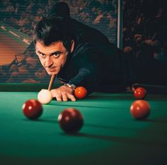 a man leaning over a pool table with balls in front of him