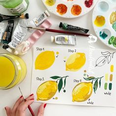 someone is painting lemons on paper with watercolors and paintbrushes next to them