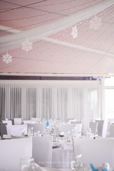 tables and chairs are set up for a wedding reception with snowflakes hanging from the ceiling