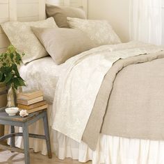 a bed with white sheets and pillows in a bedroom next to a small side table