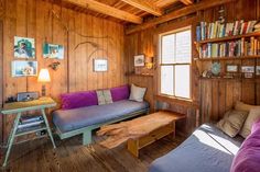 a living room filled with furniture and bookshelves next to a wooden wall covered in wood planks