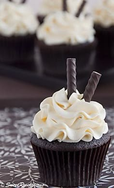 cupcakes with white frosting and chocolate sticks sticking out of them