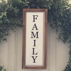 a family sign hanging on the side of a white door with greenery around it