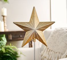 a gold star shaped lamp on a table next to a couch