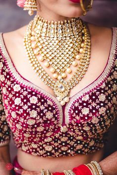 a woman in a red and gold bridal outfit with her hands on her hips