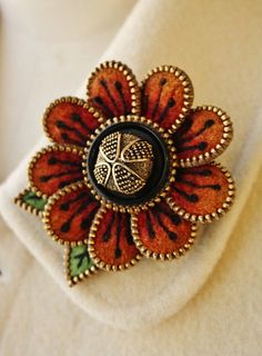 an orange and black flower brooch sitting on top of a white shirt