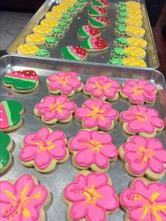 there are many decorated cookies in the tray on the table and one cookie has been cut out to look like flowers