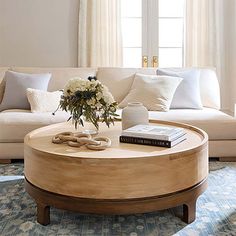 a living room filled with furniture and a coffee table on top of a rug in front of a window