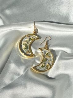 Unique Handmade Pressed Flower Crescent Moon Earrings - Artistic Craftsmanship in Silver Crafted with meticulous attention to detail, this Crescent Moon Earrings set is a true work of art. Here's a glimpse into the process: Flower Selection: Hand-selected flowers are carefully pressed and preserved to capture their natural beauty. Resin Perfection: After drying, the flowers are encased in a slow-cured resin for clarity and durability. Each piece undergoes a meticulous finishing process to addres Whimsical Gold Earrings With Moon Charm, Whimsical Gold Moon Jewelry, Whimsical Moon-shaped Gold Jewelry, Whimsical Gold Jewelry For Pierced Ears, Handmade Moon Shaped Artistic Jewelry, Handmade Moon-shaped Artistic Jewelry, Handmade Artistic Moon-shaped Jewelry, Bohemian Gold Jewelry For Mother's Day, Unique Moon Charm Earrings As Gift