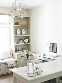 a white desk with a computer on top of it in front of a book shelf