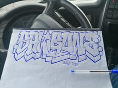 a white sign with blue graffiti on it sitting in the passenger seat of a car