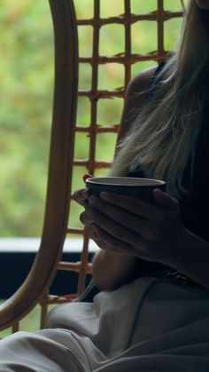 a woman sitting in a chair looking at her cell phone