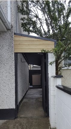 an empty alley leading to a building with a tree in the corner and one door open