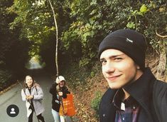 three people walking down a road in the woods