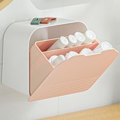 a white and pink wall mounted shelf with two compartments filled with pill holders on it