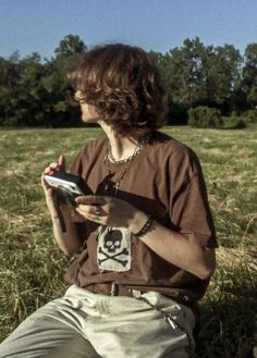 a person sitting in the grass with a remote