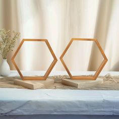 two wooden hexagonals sitting on top of a bed next to a vase