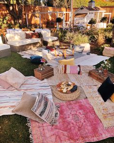 an outdoor area with lots of blankets and pillows on the ground, including a picnic table