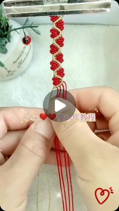 someone is making a bracelet with red thread