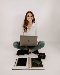 a woman sitting on the floor with her laptop in front of her and two books next to her