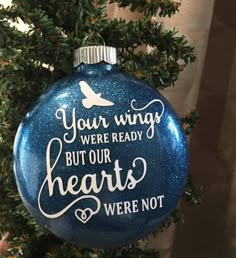 a blue ornament hanging from a christmas tree with writing on the front and back