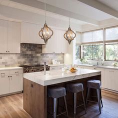 a kitchen island with three stools in front of it and an open floor plan