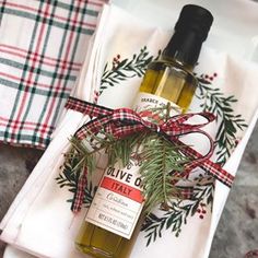 a bottle of olive oil sitting on top of a white plate next to napkins