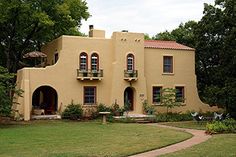 a yellow house in the middle of a grassy area with trees and bushes around it